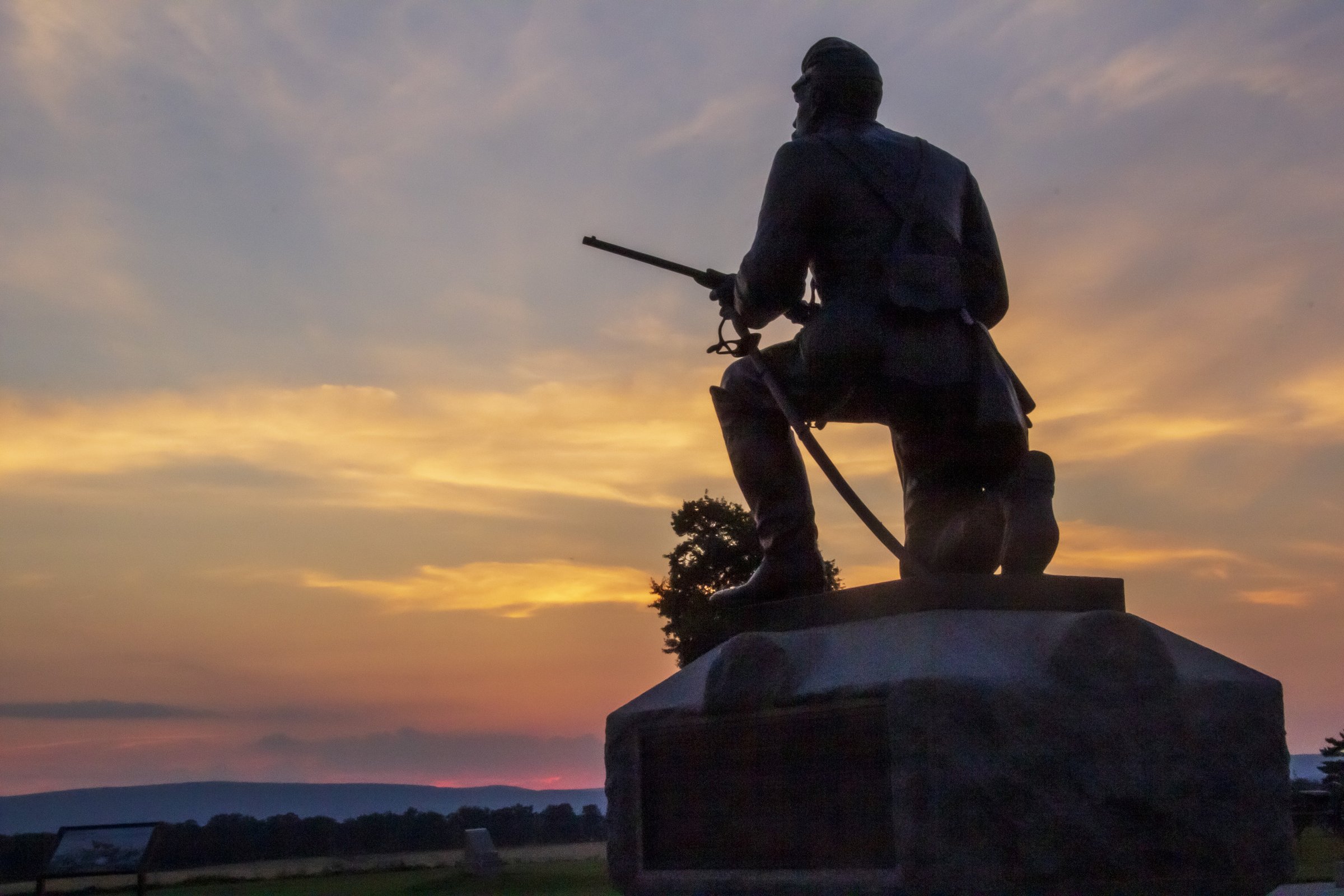 The 1st Pennsylvania Cavalry monument silhouetted against an orange sunset on the Gettysburg battlefield